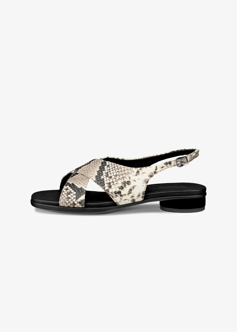 Sandal slingback dalam kulit ular faux bertekstur krim dan hitam, menampilkan desain tali silang dan tumit bulat yang rendah.
