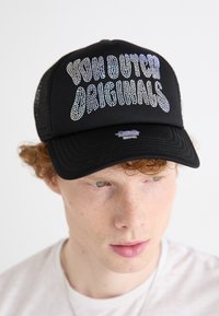 Fekete trucker sapka irizáló strasszokkal az "YON DUTCH ORIGINALS" felirattal. Hálós hátsó része és lapos napellenzője van.