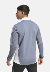 Grijs longsleeve sportshirt met witte zijpanelen en een kraag. Voorzien van een gestructureerde stof en een getailleerd ontwerp voor actieve kleding.