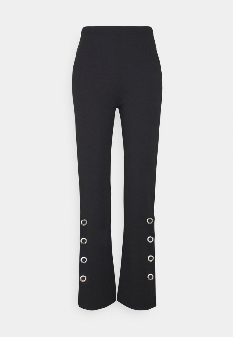 Pantalons noirs évasés avec une taille haute, comportant des œillets en métal argenté en bas et une texture de tissu lisse.