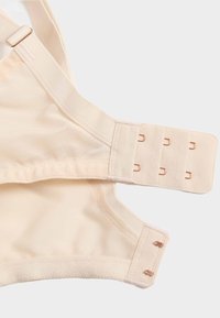 Beżowy pasek od biustonosza oraz zapięcie na haftki z trzema rzędami haczyków na materiale, widoczne szwy i regulowany metalowy suwak.