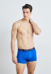 Blaue Boxershorts aus weichem Stoff mit einem schwarzen Puma-Logo-Bund. Das Design ist elastisch und tailliert und verfügt über eine glatte Textur.