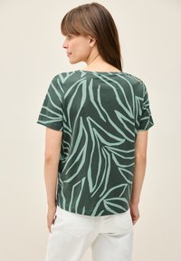 T-shirt verde a maniche corte con motivo a foglie in teal chiaro, realizzato in cotone, con una vestibilità comoda e scollatura rotonda.