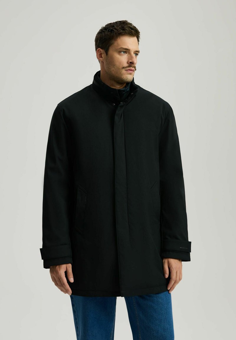 Czarny płaszcz z wysokim kołnierzem, zapinany na zatrzaski z przodu, z bocznymi kieszeniami i długimi rękawami, wykonany z gładkiego, grubego materiału.