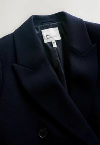 Dunkelblazer aus navy mit einer strukturierten Stoffoberfläche, scharfen Revers und einer Doppelknopfleiste. Innenausstattung mit glattem Futter und Markenlabel.