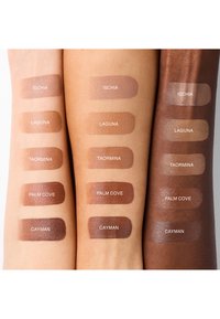 Cinq échantillons de teintes de maquillage intitulés Ischia, Laguna, Taormina, Palm Cove et Cayman sur trois bras aux tons de peau clair, moyen et foncé.