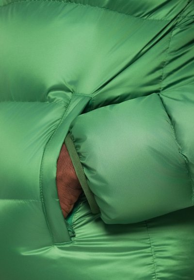 Világos zöld pufi dzseki sima textúrával, oldalzsebbel és a dzseki színével megegyező mandzsetta részletekkel.