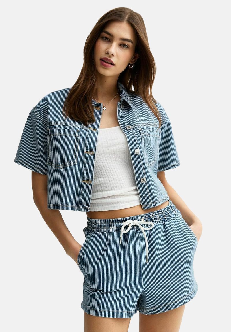 Chaqueta de mezclilla de manga corta a rayas con dos bolsillos frontales, acompañada de pantalones cortos a juego con cintura elástica y cordón.