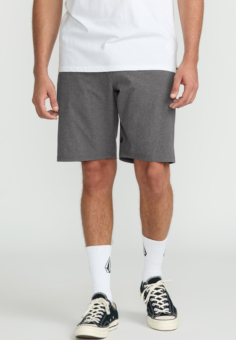 Gray shorts made of a textured fabric, featuring a relaxed fit and side pockets. Worn with white socks and black canvas sneakers.