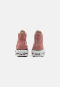 High-top pink canvas sneakers with white rubber soles, black accents, and classic All Star logo on the side. Designed for casual wear.
