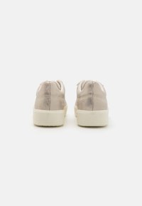 Beige Wildleder-Sneaker mit leichtem Glanz, niedrigem Profil, runder Zehenpartie und weißer Gummisohle; verfügt über ein Schnürdesign und einen gepolsterten Kragen.
