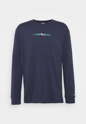 T-shirt à manches longues bleu marine en coton avec un col rond. Présente l'inscription "TOMMY JEANS" brodée en vert au-dessus d'un petit logo en rouge, blanc et bleu.