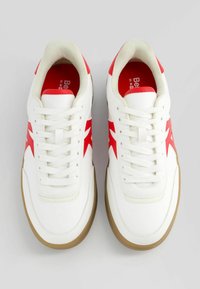 Vita sneakers med röda accenter, med en slät läderöverkant, snörning och en gummigummisula. Rund tåform och vadderad krage.