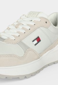 Бели и бежови маратонки с бели връзки и малко лого Tommy Jeans отстрани, с дебела бяла подметка с грайфер.