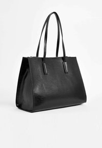 Bolso tote de cuero negro con una forma estructurada, dos asas largas y una textura suave; cuenta con un cierre de cremallera en la parte superior.