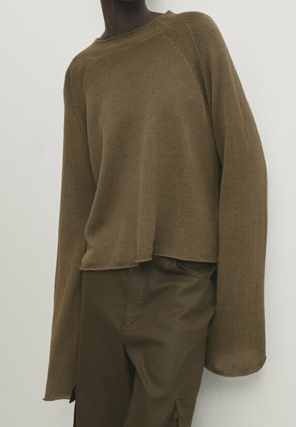 Pull en tricot marron à coupe décontractée, manches raglan et ourlet raccourci. Associé à un pantalon marron assorti, tissu texturé visible.