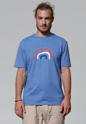 Blauwe katoenen t-shirt met een multikleurige cirkelontwerp in rood, wit en marineblauw. Korte mouwen en ronde hals. Gladde textuur.