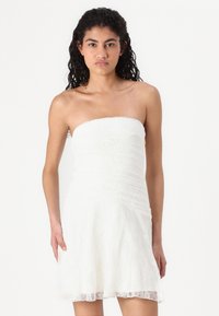 Robe blanche sans bretelles en dentelle texturée avec un corsage ajusté et une jupe évasée, présentant un motif superposé décoratif.