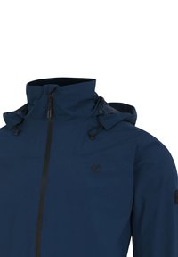 Giacca impermeabile della marina con colletto alto, cordini regolabili e logo nero sul petto. Presenta chiusura con zip e tessuto morbido e strutturato.