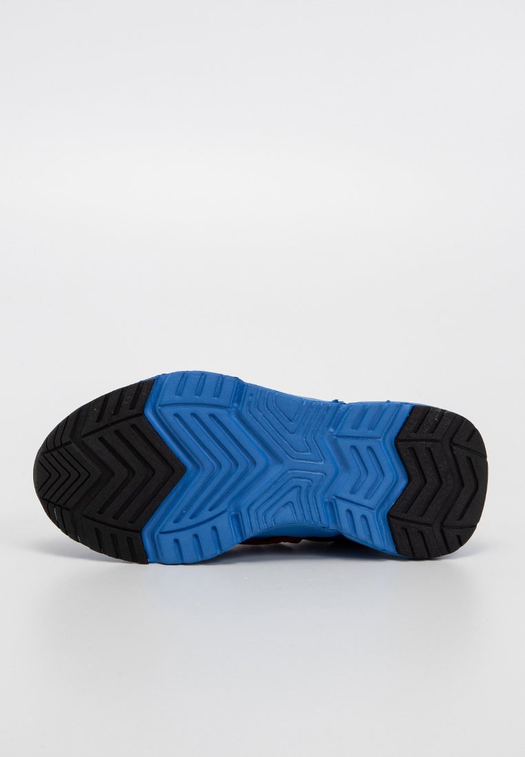 Semelle de chaussure de sport présentant un design en caoutchouc noir avec un motif texturé bleu, mettant en avant des rainures en zigzag et triangulaires pour une traction optimale.