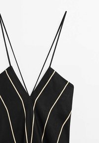 Robe noire sans manches avec un profond décolleté en V, comportant des rayures verticales crème ; fabriquée en matière légère avec des bretelles fines ajustables.