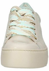Sneaker in pelle beige con suola bianca spessa, superficie texturizzata e intricate stringhe intrecciate con dettagli in oro e turchese.
