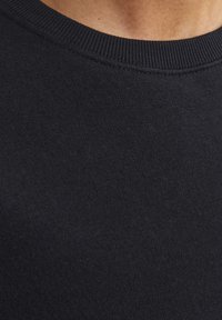 Sudadera de algodón negra con cuello redondo acanalado y textura suave. El material parece suave y transpirable, con detalles de costura sutiles.