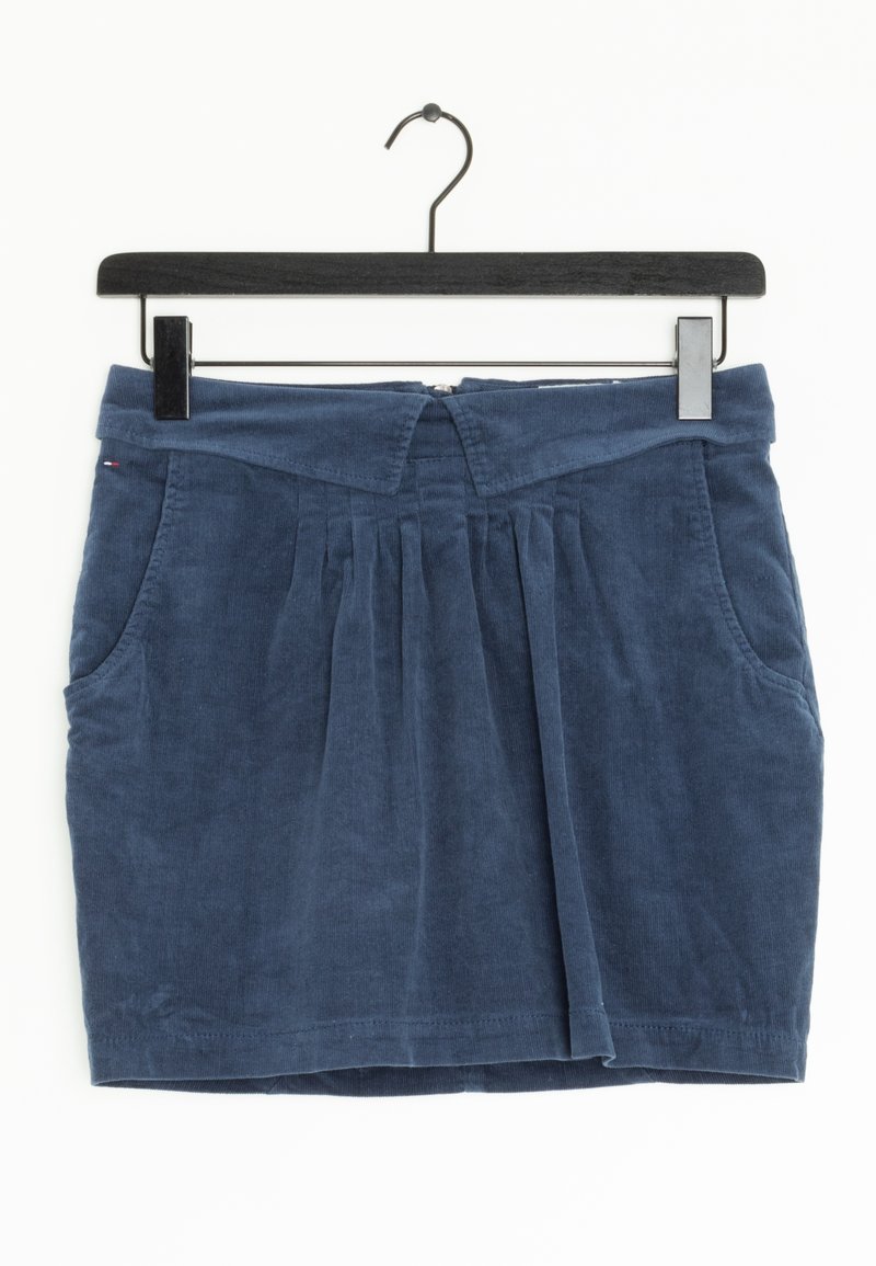Mini-jupe en velours côtelé bleu marine avec plis sur le devant, poches latérales et ceinture pliée, suspendue sur un cintre noir.