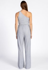 Eén-schouder jumpsuit in lichtgrijs, geribbelde textuur, wijde pijpen, elastische tailleband met geplooid detail, casual en comfortabele stijl.
