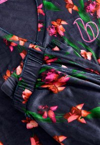 Tume kangas, millel on roosade ja oranžide toonidega lillemuster ning roheliste lehtede motiivid. Sisaldab elastset vööd ja tikitud logo detaili.