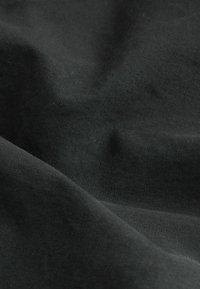 Black fabric with a smooth texture, featuring subtle creases and folds. The material appears to be a soft cotton blend.
