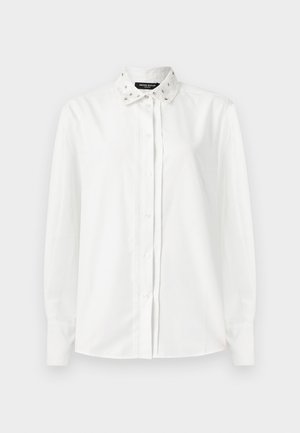 White long-sleeve shirt with a decorative, embellished collar. Features button closure and smooth fabric texture. Classic button-down design.