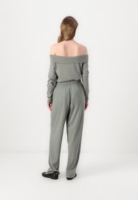 Off-the-shoulder langermet topp i dempet grønn, kombinert med matchende løs passform bukser. Mykt stoff med elastisk midjebånd.