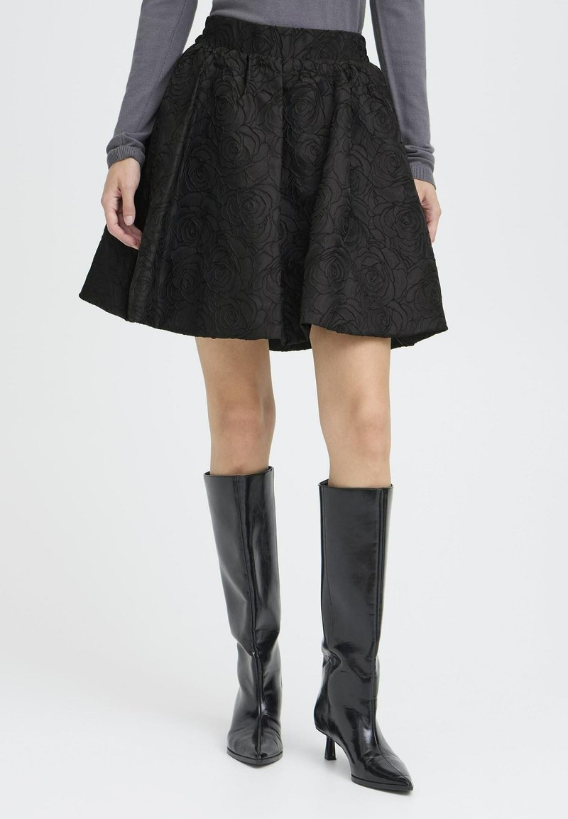 Black skirt with textured rose pattern, elastic waistband, and a flared shape. Paired with high, glossy black knee-length boots.