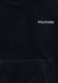 Haut à capuche bleu marine en doux tissu polaire, doté d'une poche avant et du logo "HILFIGER" brodé en blanc sur la partie supérieure gauche de la poitrine.