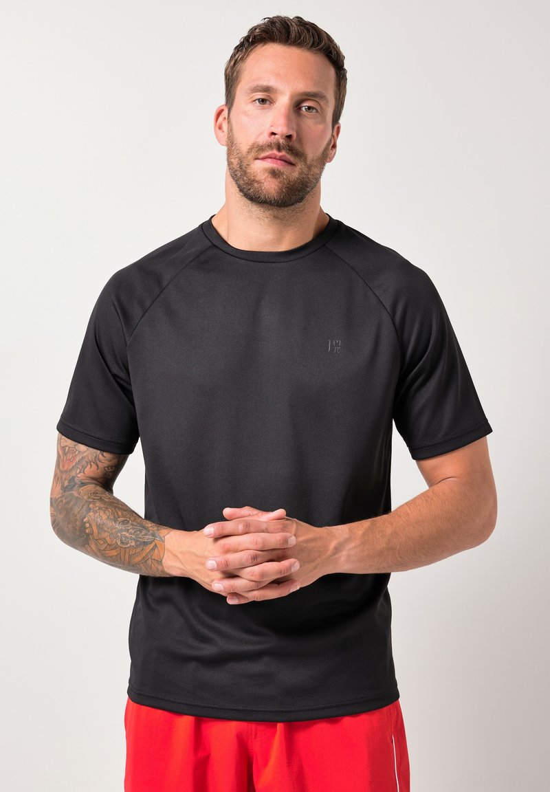Zwarte sportief T-shirt gemaakt van ademend materiaal, met een ronde hals, korte raglanmouwen en een subtiel logo op de borst.