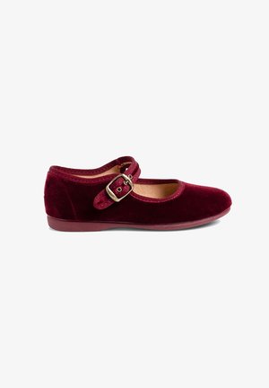 Une chaussure Mary Jane en velours rouge foncé avec une bride à boucle dorée et une semelle plate sur fond blanc.