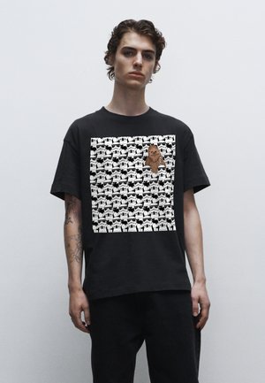 Sort bomulds t-shirt med et grafisk design, der har gentagne stormtrooper ansigtstræk og en fremtrædende Chewbacca figur i midten.