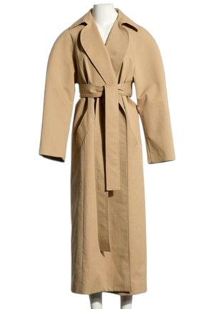 Long trench-coat beige avec larges revers, grandes manches, poches latérales et ceinture assortie à la taille sur un mannequin blanc.