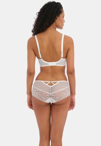Witte lingerieset met een gladde beha met verstelbare bandjes en een kanten achterkant, gecombineerd met bijpassende witte shorts met kantafwerking.