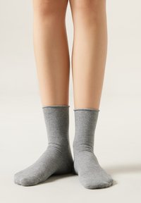 Calcetines de algodón grises hasta el tobillo con puño acanalado. Textura suave, diseño casual, se ajusta cómodamente por encima del tobillo.