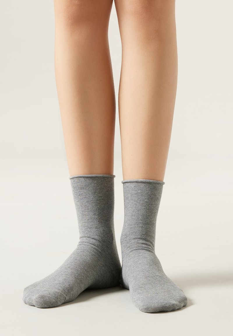 Calcetines de algodón grises hasta el tobillo con puño acanalado. Textura suave, diseño casual, se ajusta cómodamente por encima del tobillo.