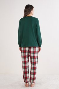Blusa verde de manga larga combinada con pantalones de pijama de cuadros en rojo, verde y blanco. Corte suave y relajado con puños elásticos.