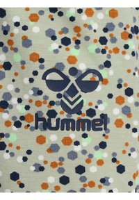 Patroonstof in lichtgroen met hexagonale en cirkelvormige vormen in marineblauw, oranje, wit en mint. Opvallend logo met de tekst "hummel."