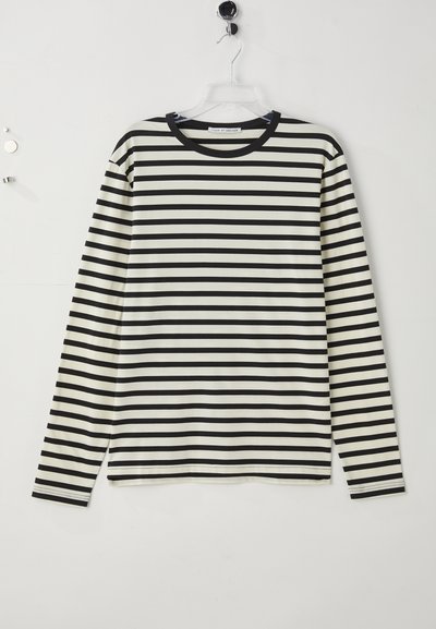 Camiseta de manga larga con rayas horizontales negras y blancas colgada en una percha de plástico transparente contra una pared blanca.