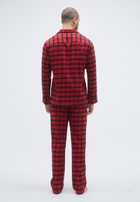 Czerwono-czarny zestaw piżam w kratę, z długimi rękawami i spodniami z miękkiego materiału, z bluzką zapinaną na guziki i luźnym krojem.