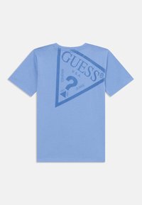 T-shirt bleu clair en coton, avec un grand graphique triangulaire "GUESS" imprimé en bleu marine au dos. Manches courtes et col rond.