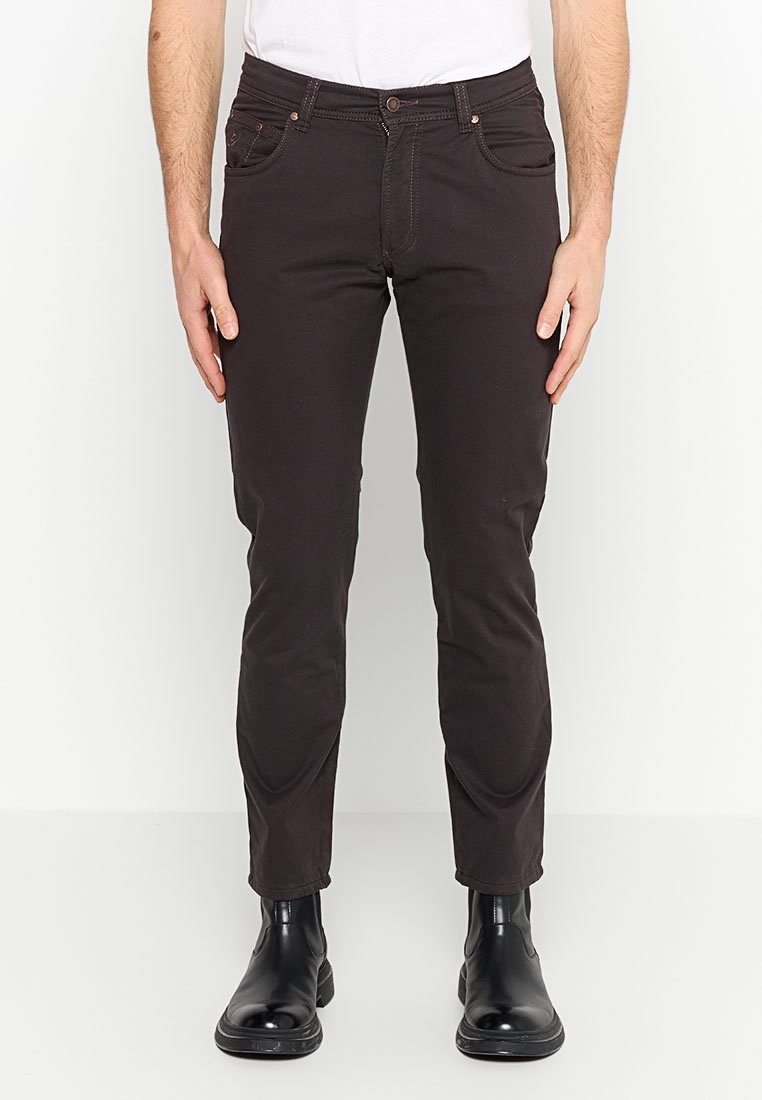 Ciemnobrązowe slim-fit spodnie wykonane z mieszanki bawełny, z pięcioma kieszeniami, subtelnym przeszyciem, noszone z czarnymi botkami za kostkę.