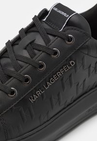 Svarta lädersneakers med texturerat mönster, snörning och silverdetaljer. Har en logotags på tungan.