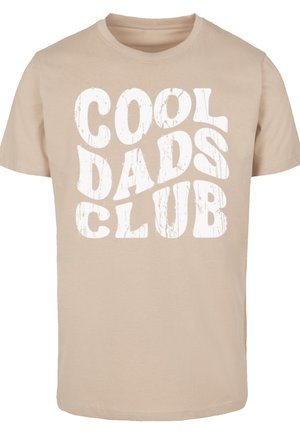 Camiseta beige de algodón con mangas cortas. Presenta un gran gr�áfico en blanco con la frase "CLUB DE PAPÁS GENIALES" en una fuente gruesa y desgastada.
